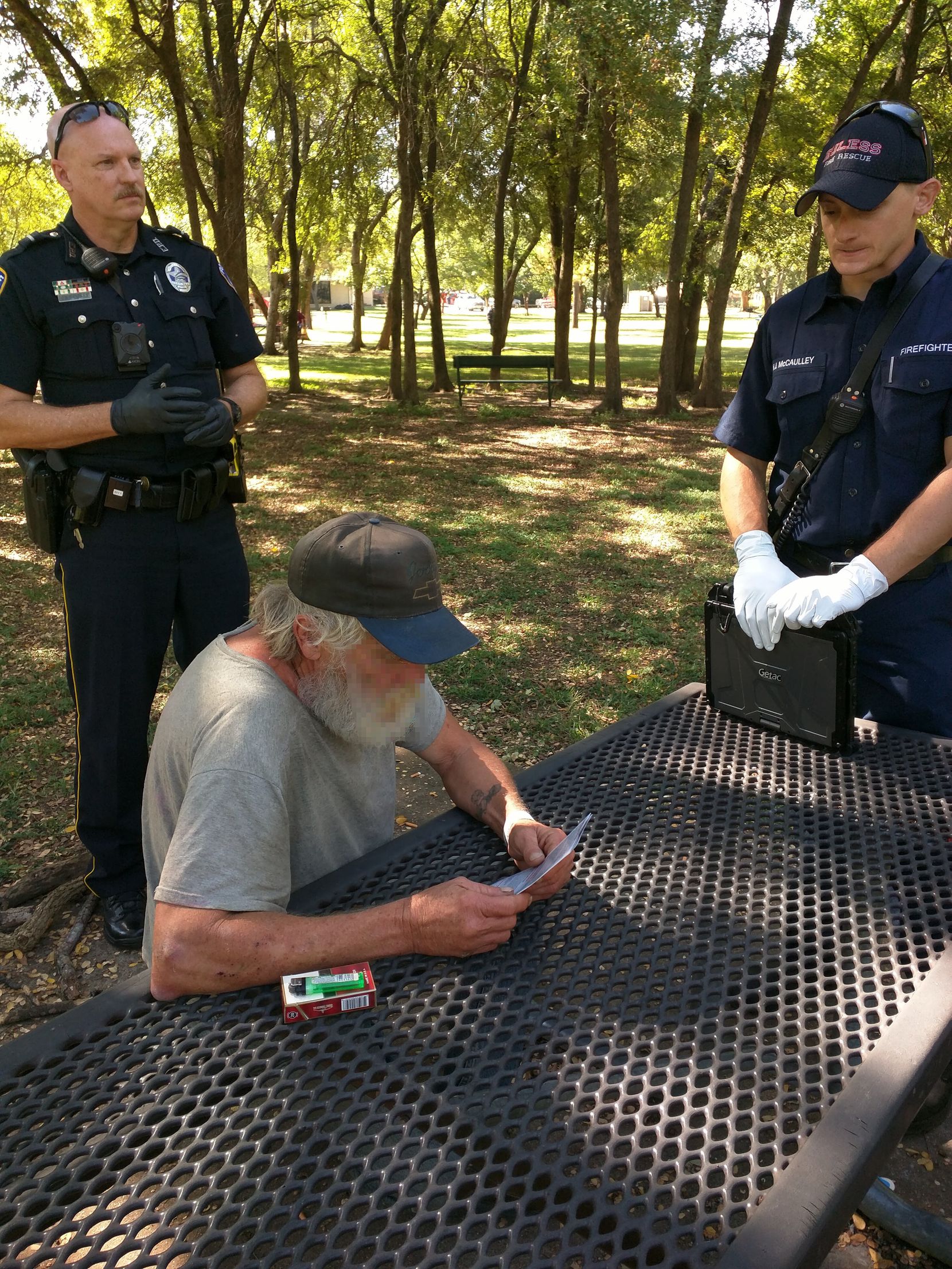 Euless Officer Casey Sanders (left), andan EMT (right) speak with Floyd (center) about his options before transporting him to JPS.